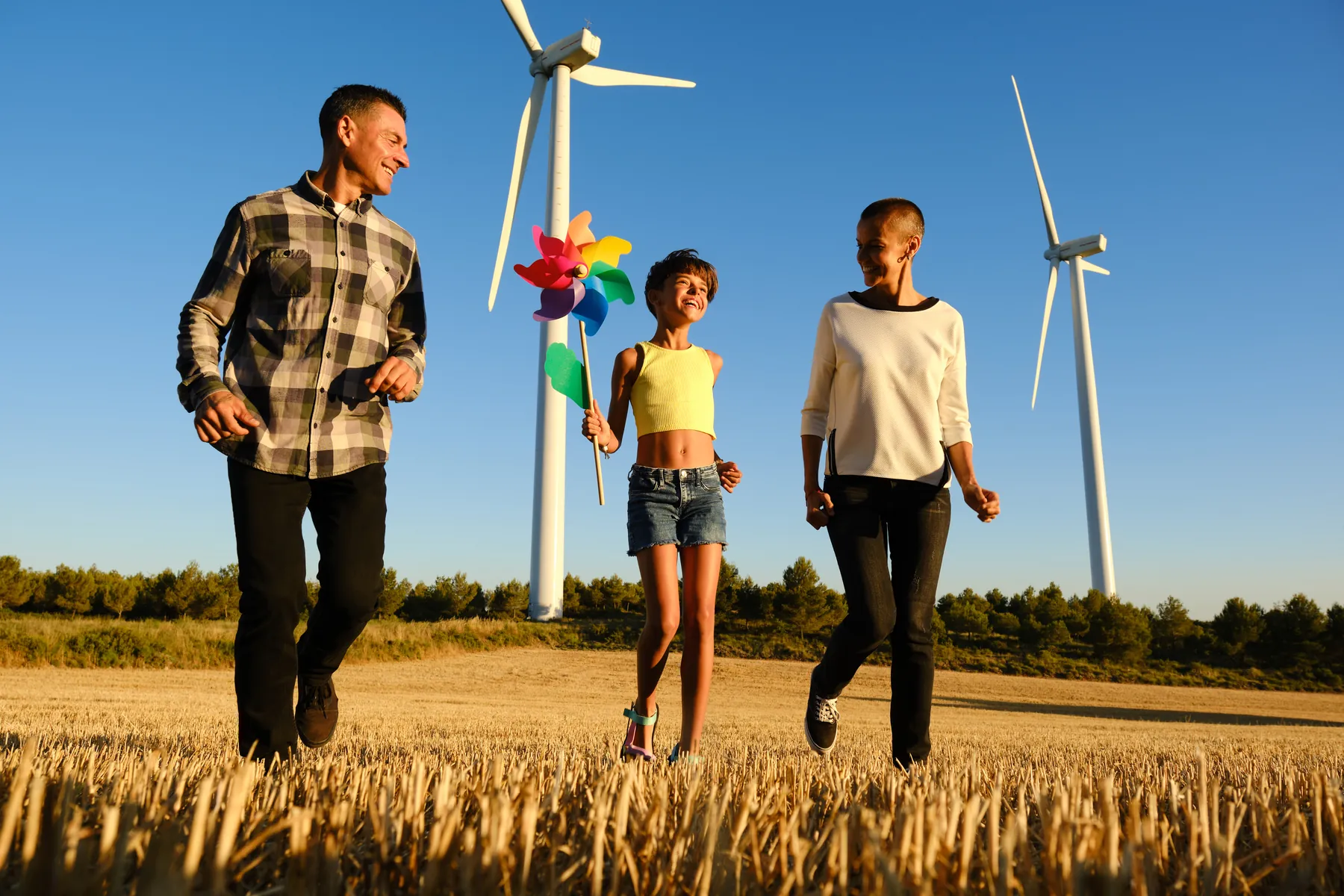 A family walking among wind turbines