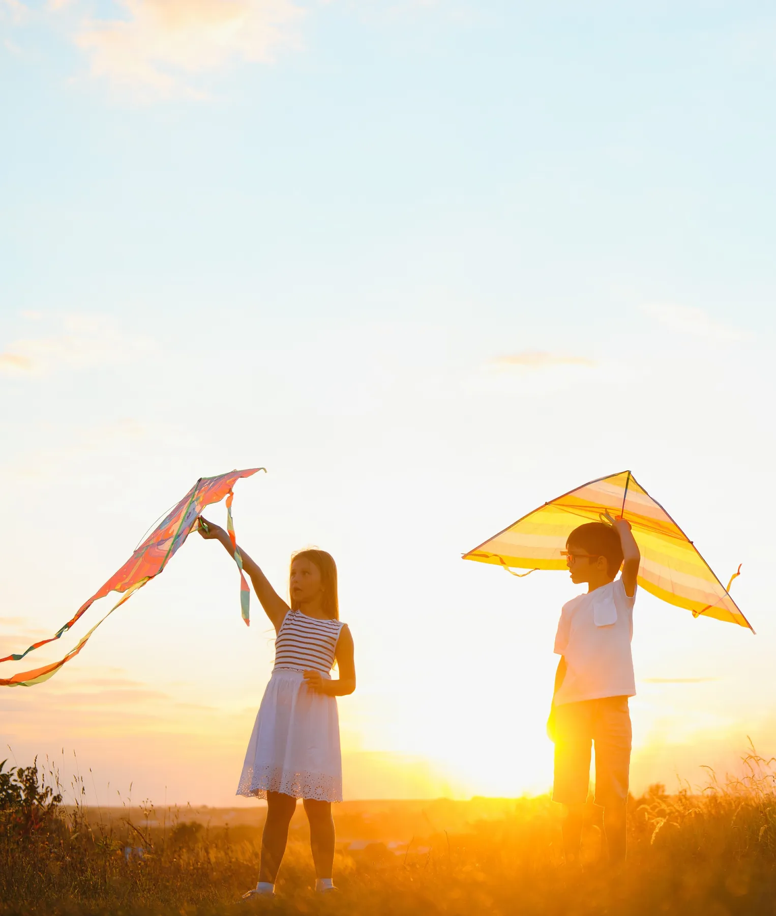 Children flying kites at sunset